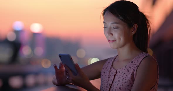 Woman use of mobile phone at beautiful sunset time