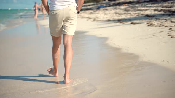 Guy Relaxing On Tropical Beach Resort In Honeymoon Vacation Holiday. .Man Legs Walking On Beach.