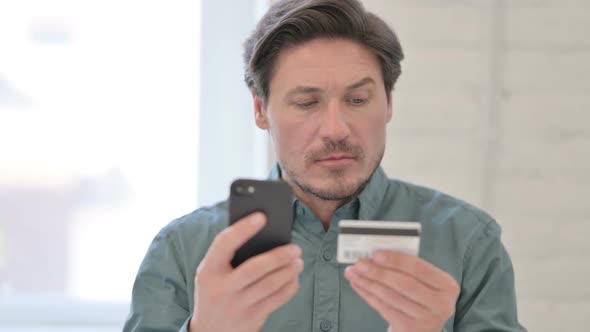 Portrait of Middle Aged Man with Successful Online Shopping on Smartphone