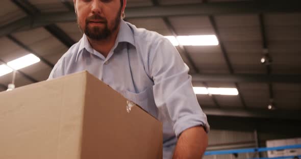 Male worker arranging box in warehouse