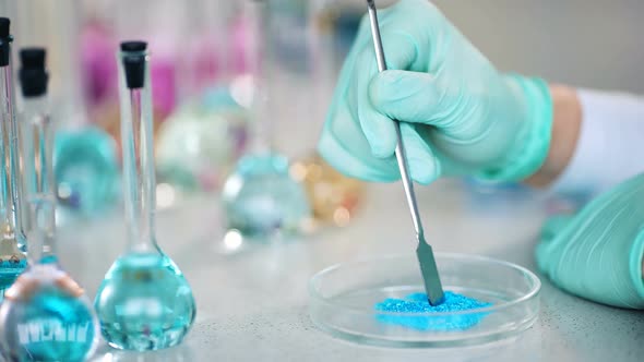 Closeup of Scientist's Hand Preparing Powder on Glass Dish for Some Research in a Laboratory