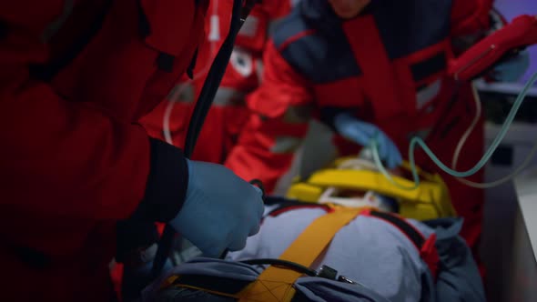 Paramedics Team Examining Patient with Stethoscope in Emergency Car