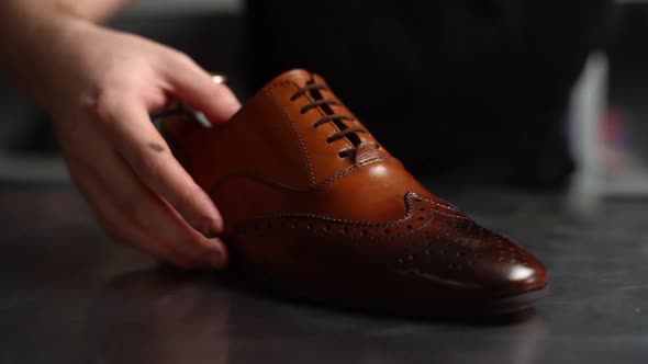 Closeup Hands of Male Shoemaker Puts Old Light Brown Leather Shoe Near Repaired Shiny