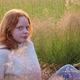 Cute Beautiful Teenager Girl with Long Red Hair Sitting on the Grass on Summer Field Enjoying the - VideoHive Item for Sale
