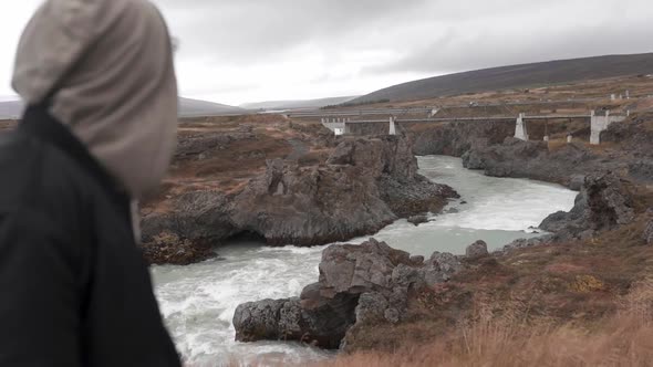 Traveler admiring view of bridge over river in highlands