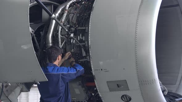 Engineer, technician examines the jet engine with a flashlight. 