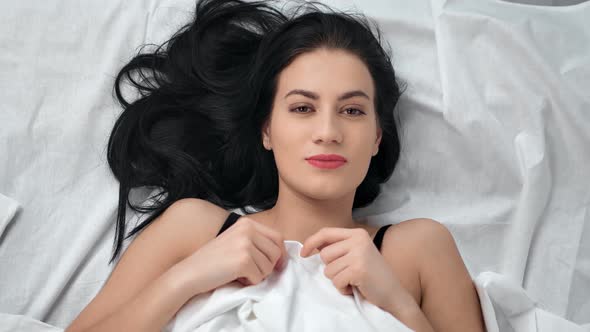 Portrait of Pretty Brunette Young Smiling Woman Lying on Bed