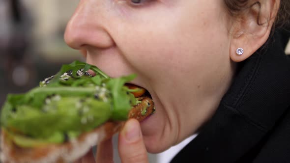 Close Up of a Caucasian Girl Taking a Bite of Healthy Vegan Avocado Toast with Great Appetite