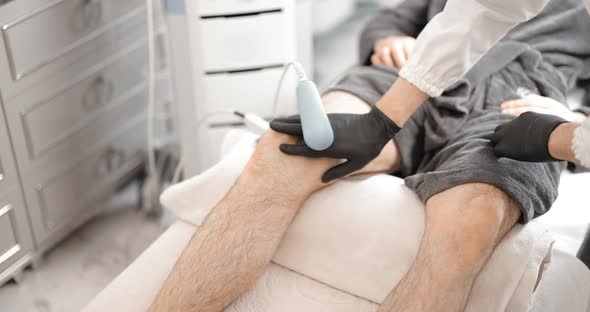 Doctor Doing Magnetic Therapy on Male Knee