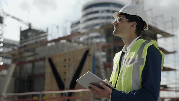 Man in Helmet Working on Tablet at Construction Plan