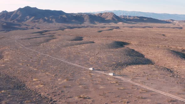 Two SUVs drive through desert - Tecopa, CA - Aerial