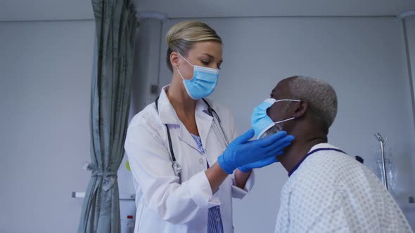 Caucasian female doctor wearing face mask examining throat of african american senior male patient