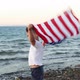 boy waving national USA flag at sea over the blue sky - VideoHive Item for Sale