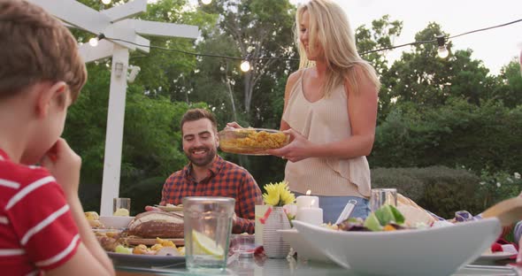 Young woman serving food to family members outdoors