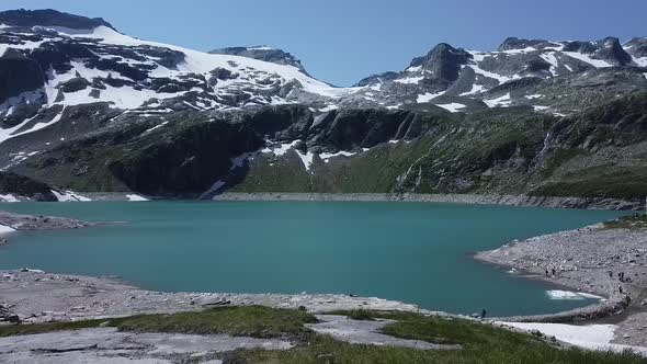 Flying towards a beautiful blue lake with snow and ice in the Austrian Alps, Uttendorf Weissee