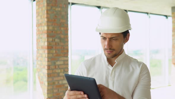 Engineer Builder Architect with Safety Helmet with Tablet Looking on New Building on Site