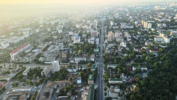 Aerial drone view of Chisinau at sunrise. Multiple buildings, trees, park, roads with cars. Moldova