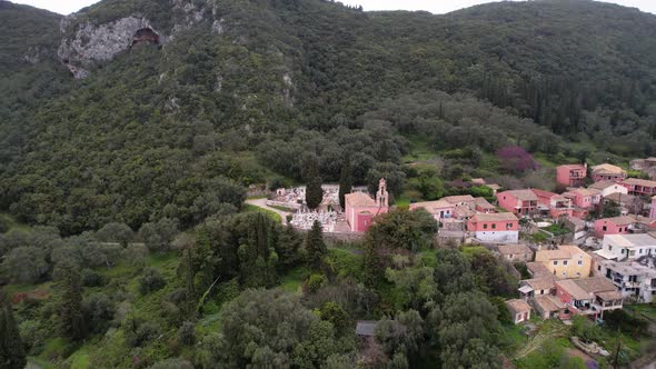 Clockwise rotating shot of old greek church with cementary on top of mountain village. Village surro