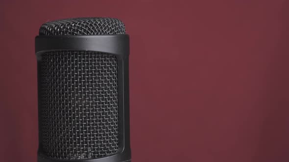 Studio Condenser Microphone Rotates on Red Background with Place for Text