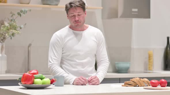 Serious Man Feeling Worried While Standing in Kitchen