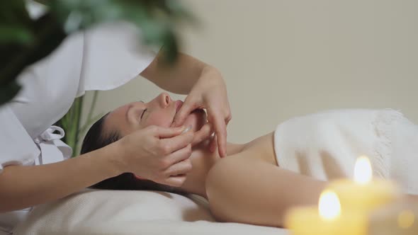 Beautiful Brunette Woman in Spa Salon on Massage with Gouache Stones