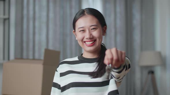 Young Asian Woman With Cardboard Boxes Smiling And Showing The Keys To Camera In The New House