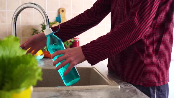 Reusable glass water bottle. Man pours water from the tap. Zero Waste Lifestyle