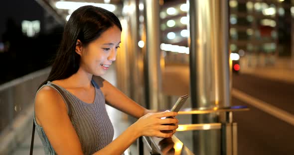 Woman looking at mobile phone in the city at night 