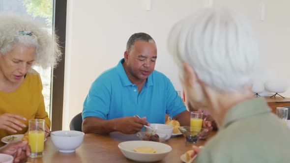 Happy senior diverse people having breakfast at retirement home