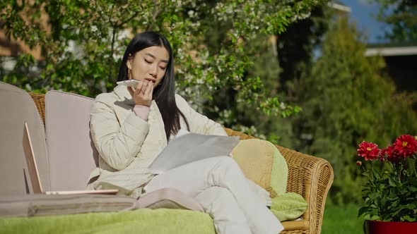 Intelligent Beautiful Young Asian Woman Recording Voice Mail Sitting on Couch in Sunny Garden