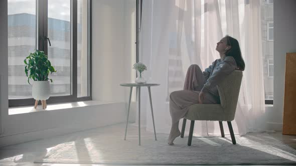 Young Inspired Woman Listening Music in Wireless Headphones and Stands Up From the Chair