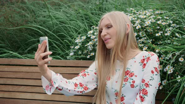 Woman Making Video Call on Green Roof. Lovely Young Female Using Smartphone To Make Video Call While