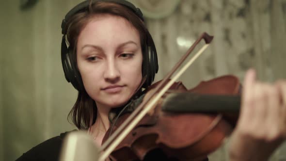 Happy Violinist with Headphones Playing the Violin During a Rehearsal