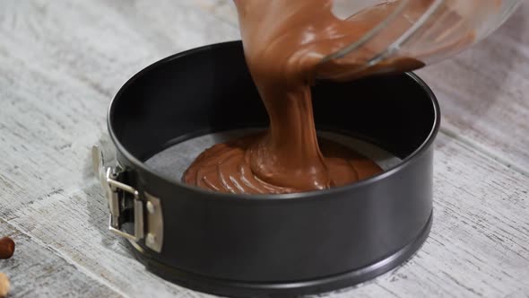 Pouring chocolate batter into pan. Woman in the kitchen making chocolate cake.	