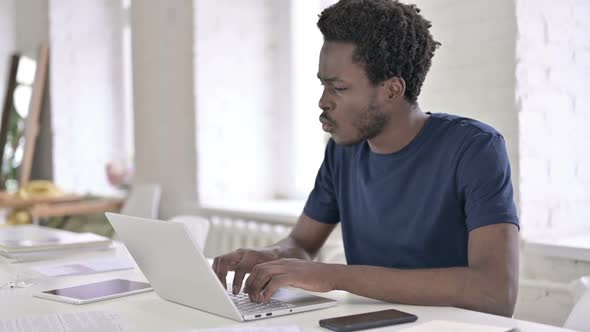 Surprised African Man Having Success on Laptop