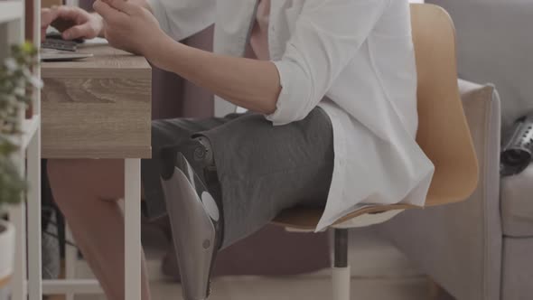 Businessman with Prosthetic Leg Working on Computer at Home Office