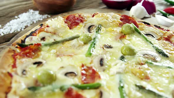 Italian pizza on wooden table with vegetables and spices