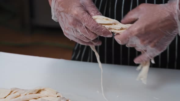 A Man Worker Rips Mozzarella Cheese Into Pieces