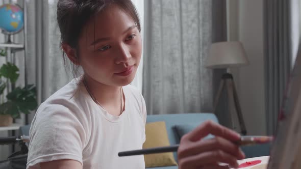 Asian Artist Girl In Wheelchair Holding Paintbrush And Mixing It With Colour Before Painting