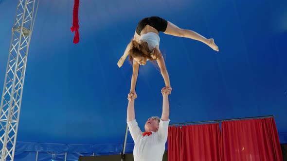 Female acrobat performing handstand on hands of partner