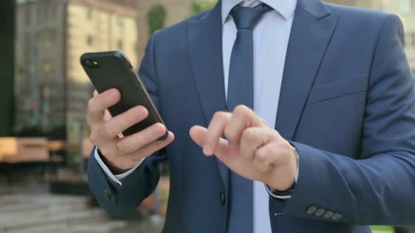 Hands Close up of Businessman using Smartphone while Walking in Street