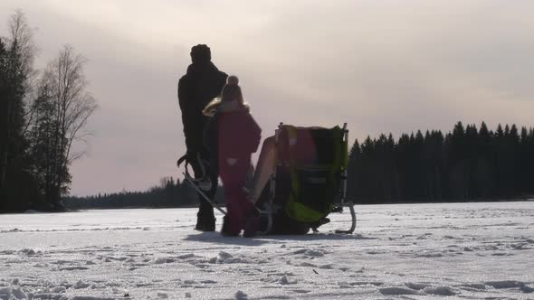 Silhouette dad dragging sled with kids in winter landscape