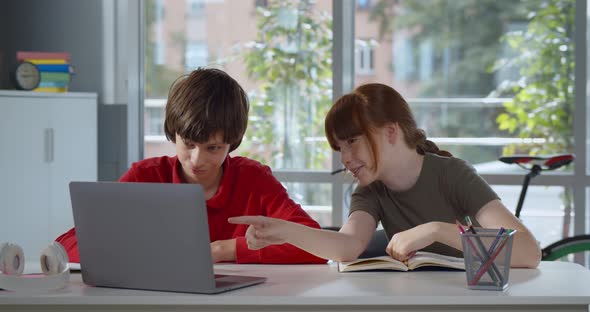 Teen Children Working Together at Desk in Classroom at Modern School Using Laptop