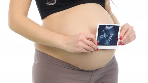 Pregnant Woman Holding an Ultrasound Scan of Her Baby, White, Closeup