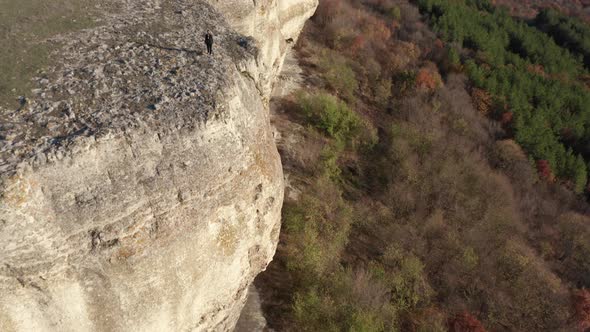 Rear view of a young blonde woman, walking along the edge of stunning rock formation