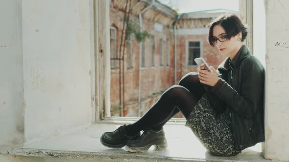 Young Hipster Woman Sitting on a Window Sill in an Old Building