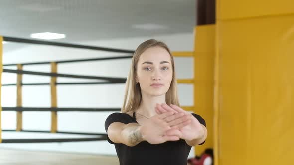 woman does active squats with legs outstretched hands near Boxing ring