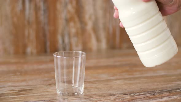 Female Hand Pouring Milk From Bottle To Glass