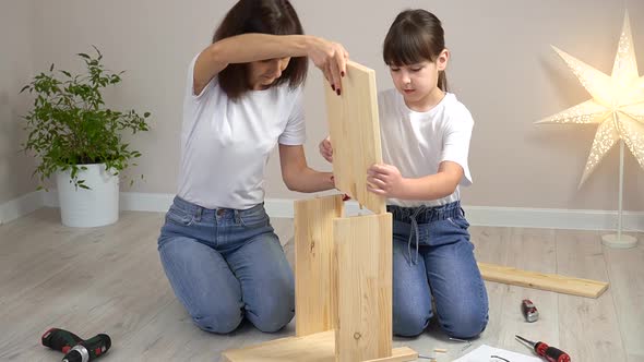 Happy Family Mother and Daughter Assembling Wooden Furniture Together