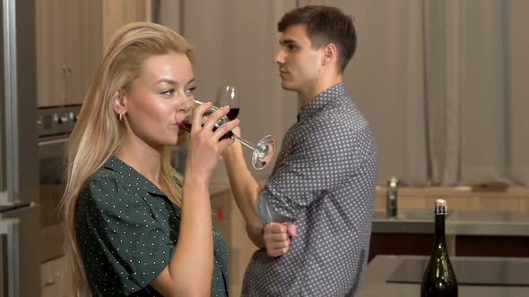 Gorgeous Woman Drinking Wine at Home, Her Boyfriend Looking at Her Seductively